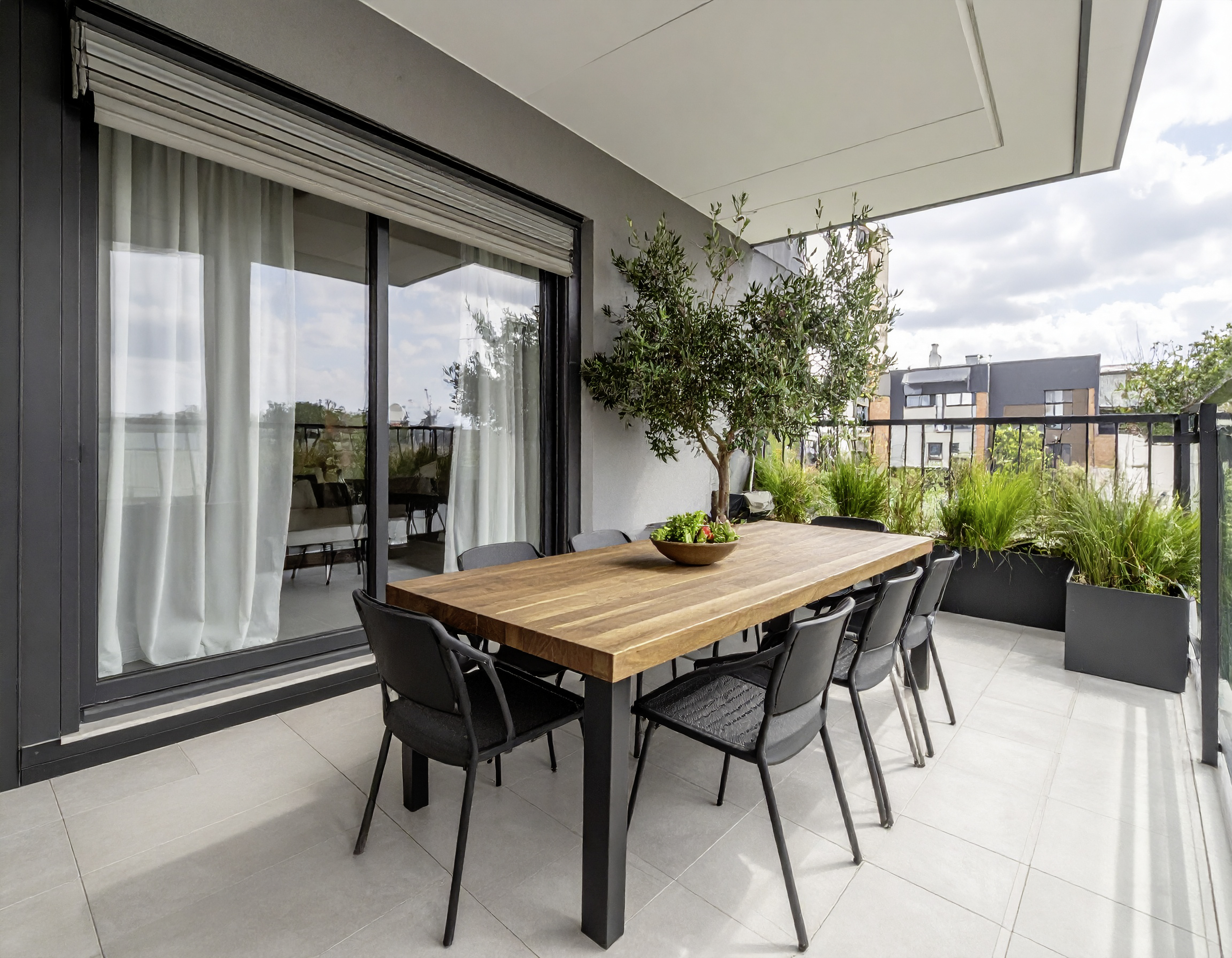 Große Terrasse mit Holztisch, acht Stühlen und grünen Pflanzen in Pflanzkübeln