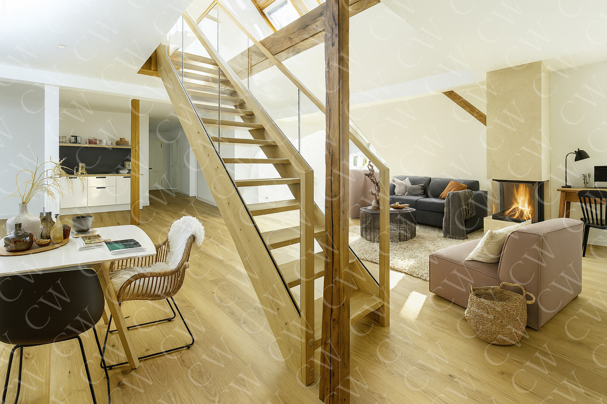 Helles Wohnzimmer mit moderner Holztreppe, Kamin, Sofa und gemütlicher Einrichtung.