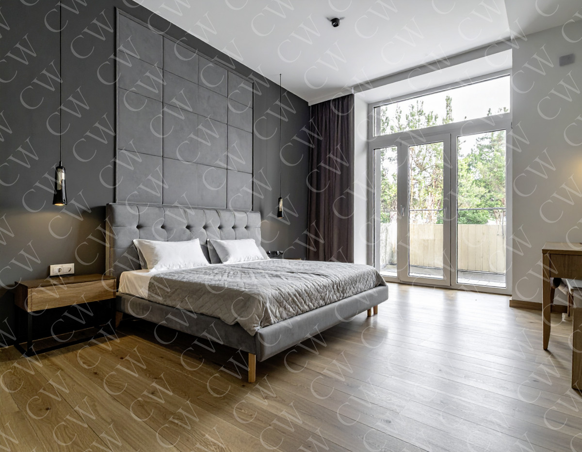 Modern eingerichtetes Schlafzimmer mit grauem Bett, Holzboden und bodentiefem Fenster.