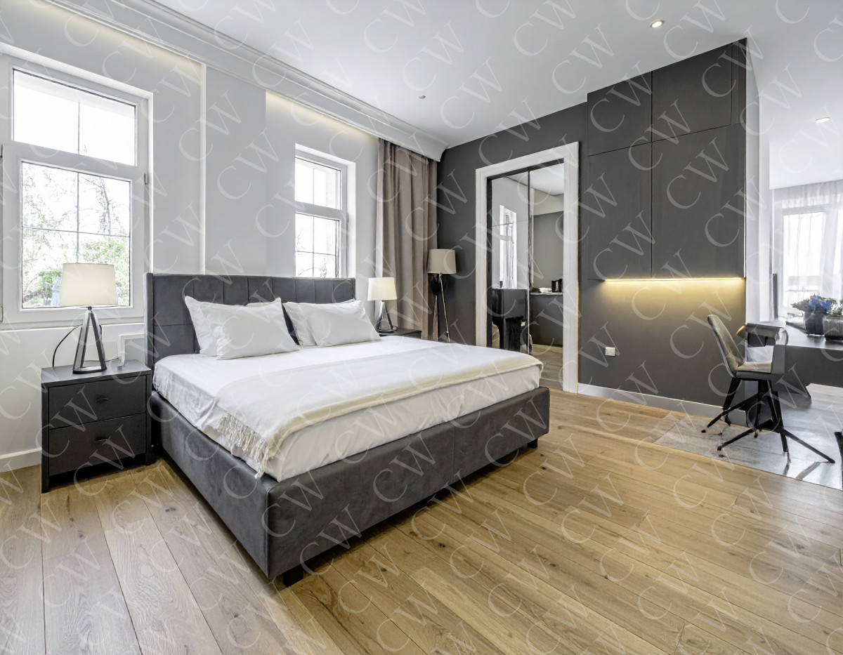 Modern eingerichtetes Schlafzimmer mit großem Bett, Holzfußboden und Schreibtisch.