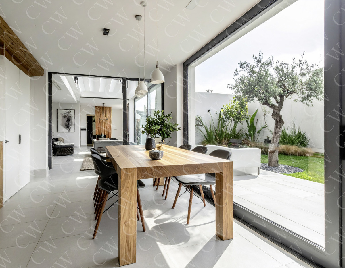 Helles Esszimmer mit Holztisch, schwarzen Stühlen und Blick in einen modernen Garten.