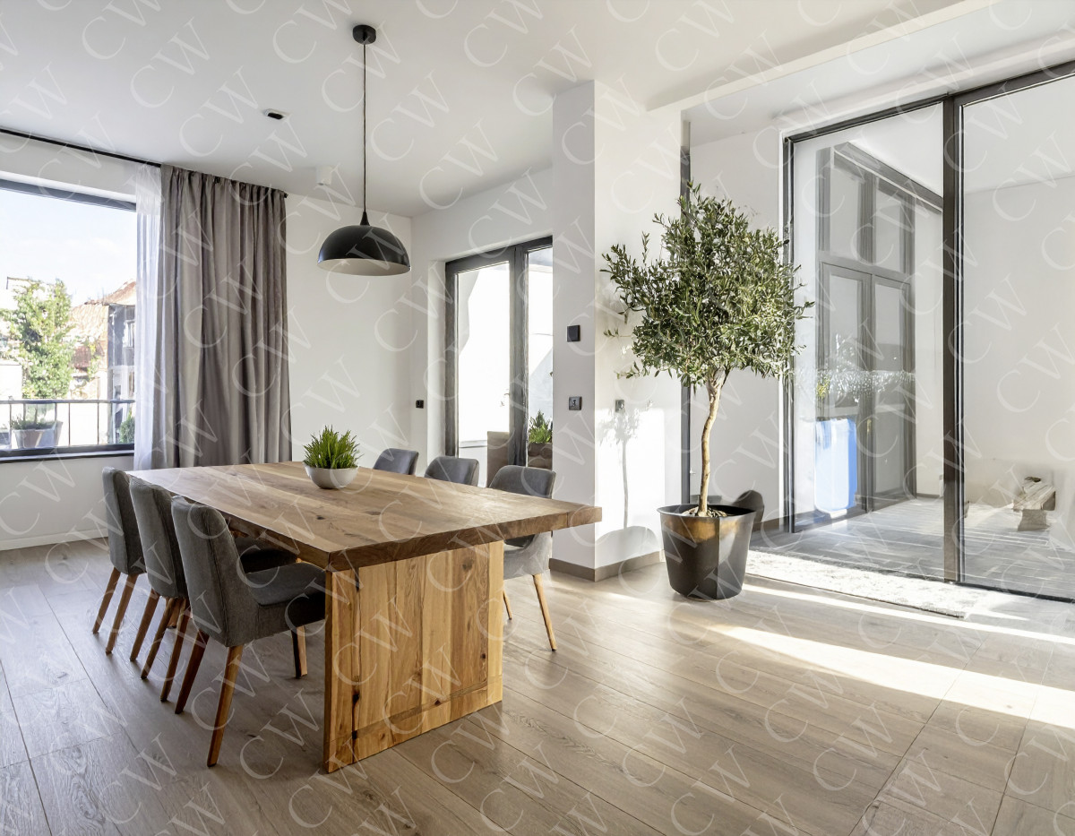 Helles, modernes Esszimmer mit großem Holztisch, grauen Stühlen und Fensterfront.