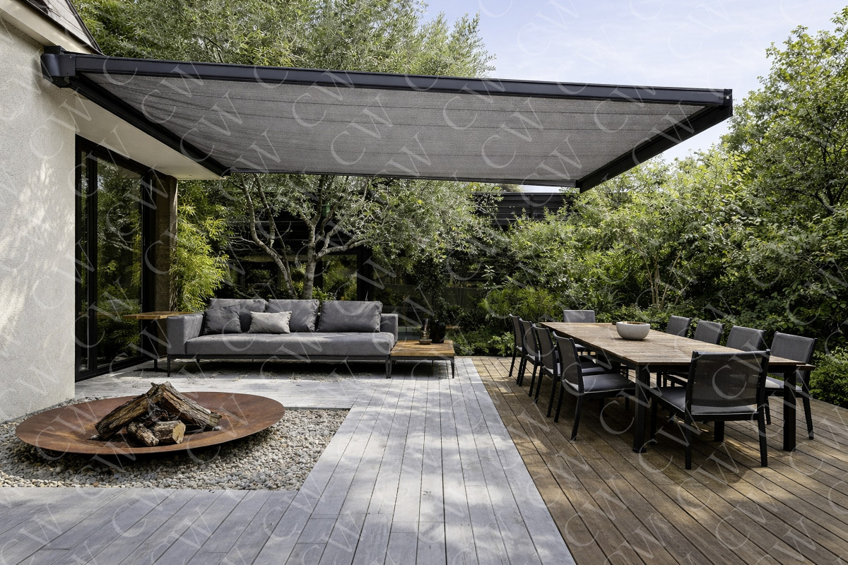 Große Terrasse mit Markise, Lounge-Sofa, Esstisch, Stühlen und Feuerstelle im Grünen.