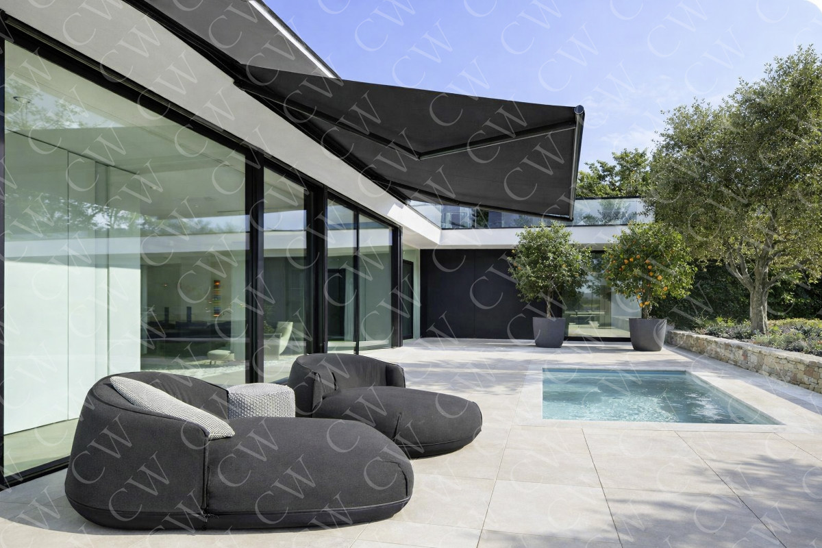 Große moderne Terrasse mit schwarzer Markise, Pool und bequemen Loungemöbeln vor einer Glasfassade.