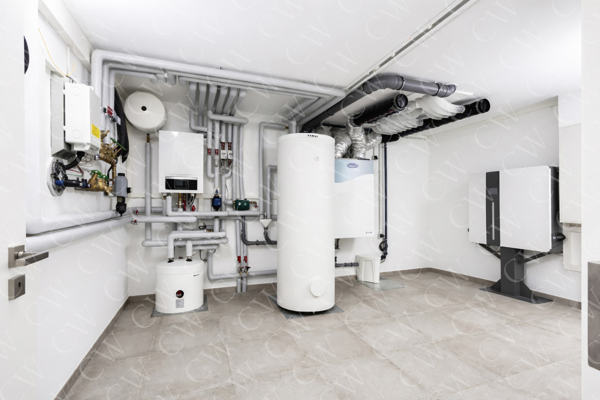 Heizungsraum mit moderner Wärmepumpe, Pufferspeicher und Lüftungsanlage.